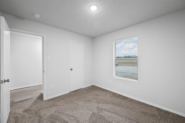 carpeted empty room with a textured ceiling