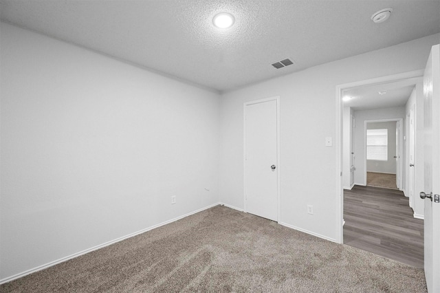 carpeted empty room with a textured ceiling