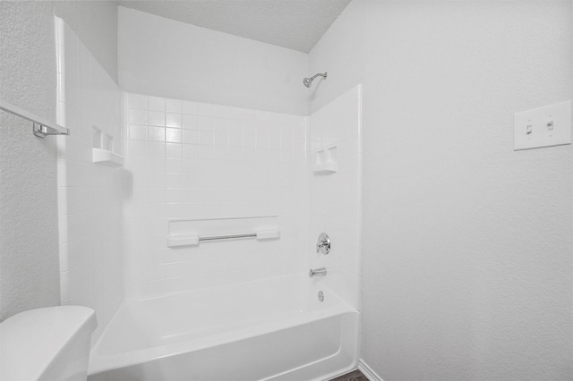 bathroom with shower / tub combination, toilet, and a textured ceiling