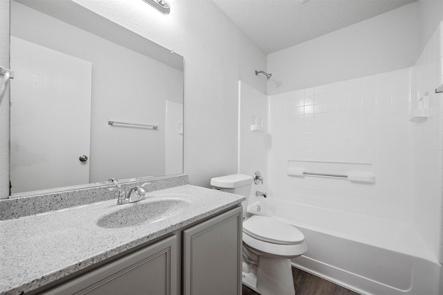 full bathroom featuring hardwood / wood-style floors, washtub / shower combination, vanity, toilet, and a textured ceiling