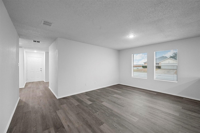 empty room with a textured ceiling and dark hardwood / wood-style flooring