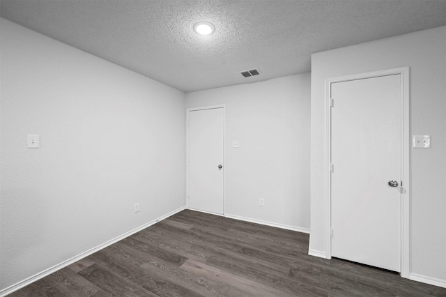 unfurnished room featuring dark wood-type flooring and a textured ceiling