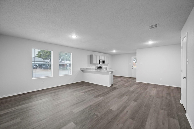 unfurnished living room with dark wood-type flooring and a textured ceiling