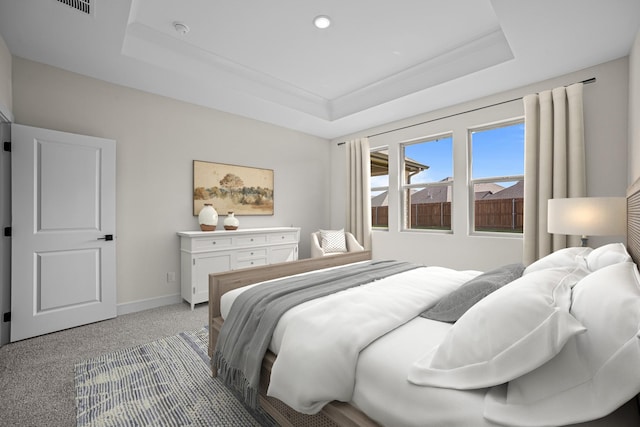 carpeted bedroom featuring baseboards and a raised ceiling