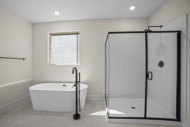 full bath featuring baseboards, a soaking tub, tile patterned flooring, and a stall shower