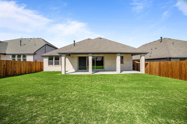 back of property with a fenced backyard, brick siding, a yard, and a patio