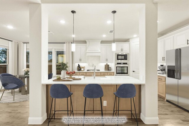 1130 Cardinal Dr, Midlothian, TX 76065 - kitchen featuring appliances with stainless steel finishes, custom range hood, light wood-type flooring, a kitchen bar, and recessed lighting