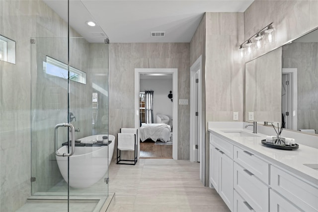 bathroom with vanity, separate shower and tub, and tile walls