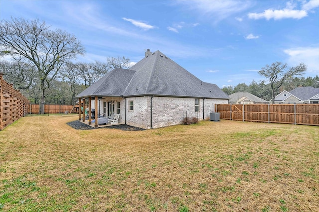 rear view of house with central AC, a patio, and a lawn