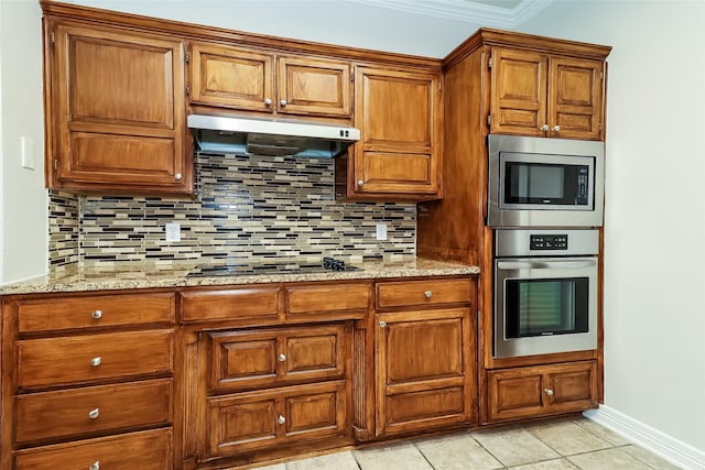 kitchen featuring tasteful backsplash, appliances with stainless steel finishes, light stone countertops, and exhaust hood