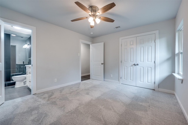 unfurnished bedroom with ceiling fan, ensuite bath, light carpet, and a closet