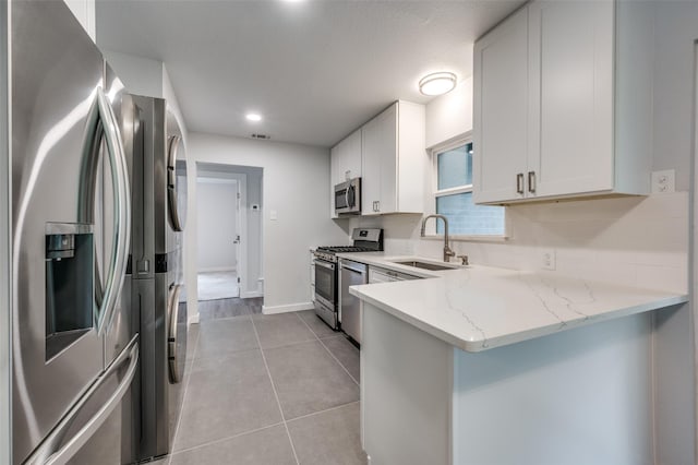 kitchen with sink, stainless steel appliances, light stone countertops, and white cabinets