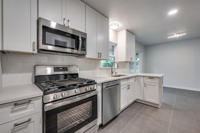 kitchen with light tile patterned floors, sink, white cabinetry, stainless steel appliances, and kitchen peninsula