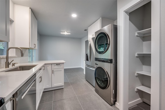 laundry area with sink, stacked washer and clothes dryer, and tile patterned floors