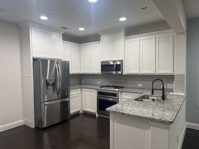 kitchen featuring sink, light stone counters, appliances with stainless steel finishes, dark hardwood / wood-style flooring, and white cabinets