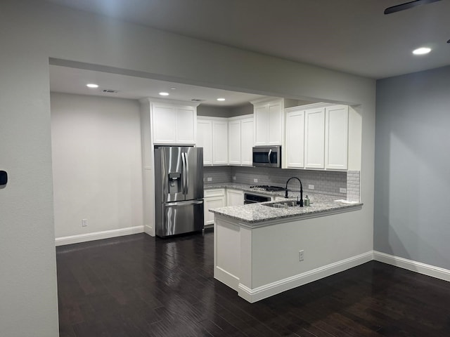 kitchen featuring sink, white cabinets, stainless steel appliances, light stone countertops, and backsplash