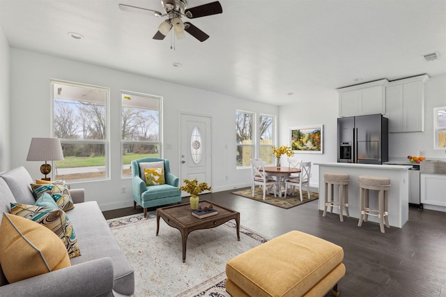 living area featuring ceiling fan, dark wood-style flooring, visible vents, and baseboards