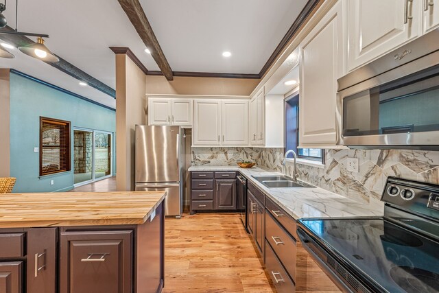 kitchen featuring appliances with stainless steel finishes, sink, wooden counters, white cabinetry, and tasteful backsplash