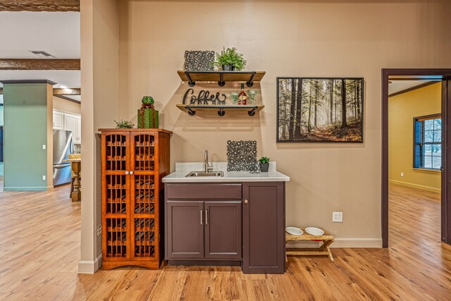 bar with sink, stainless steel fridge, and light hardwood / wood-style floors