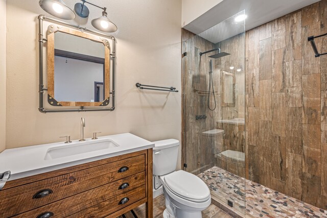 bathroom with toilet, vanity, and tiled shower