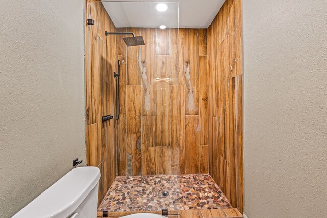 bathroom featuring a tile shower and toilet