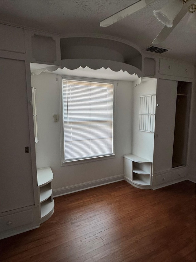 unfurnished bedroom featuring ceiling fan, a textured ceiling, and dark hardwood / wood-style flooring