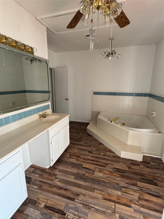 bathroom with vanity, tiled tub, hardwood / wood-style flooring, and ceiling fan