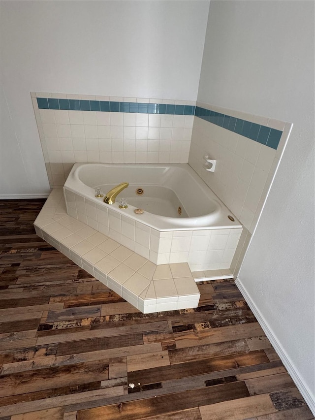 bathroom featuring wood-type flooring and tiled bath