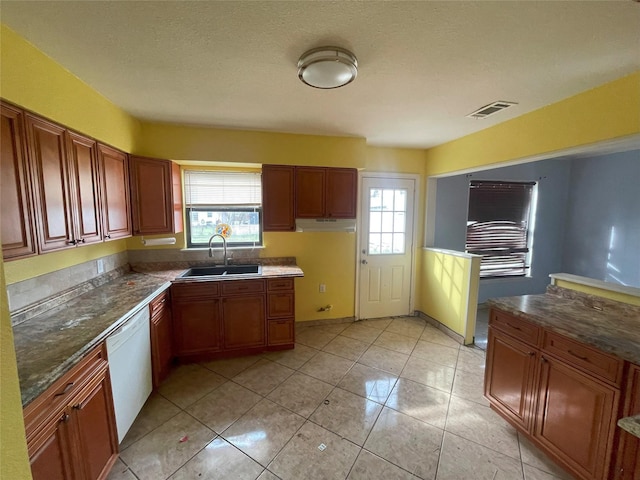 kitchen featuring plenty of natural light, white dishwasher, sink, and light tile patterned floors