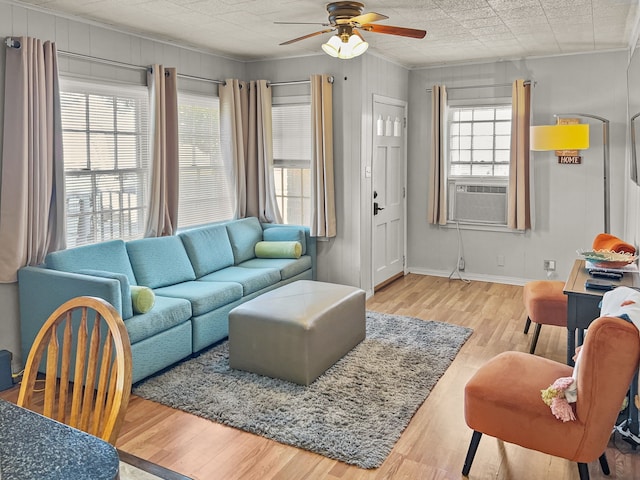 living area featuring baseboards, ceiling fan, cooling unit, and wood finished floors