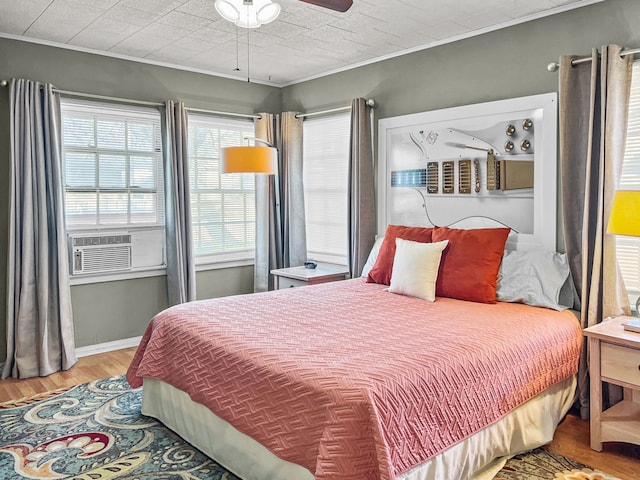 bedroom with baseboards, a ceiling fan, ornamental molding, wood finished floors, and cooling unit