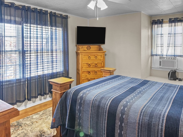 bedroom with crown molding, a ceiling fan, cooling unit, and wood finished floors