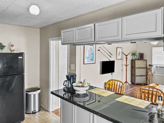 kitchen featuring tile countertops, freestanding refrigerator, cooling unit, white cabinetry, and light tile patterned flooring