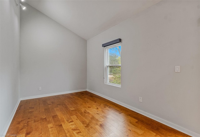 unfurnished room with hardwood / wood-style flooring and lofted ceiling