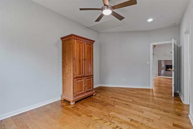 8216 Coolgreene Dr, Dallas, TX 75228 - unfurnished room featuring ceiling fan, attic access, light wood-style flooring, baseboards, and a warm lit fireplace