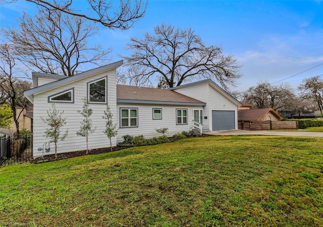 view of front of home with an attached garage, concrete driveway, a front yard, and fence