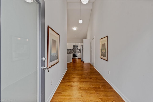 hall with a towering ceiling and light hardwood / wood-style floors