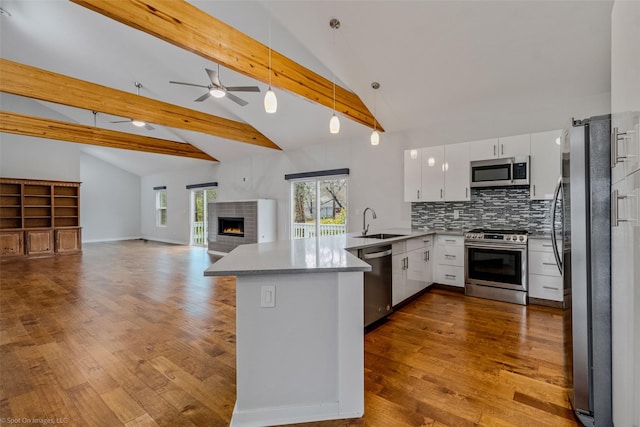 kitchen featuring decorative light fixtures, white cabinetry, sink, kitchen peninsula, and stainless steel appliances