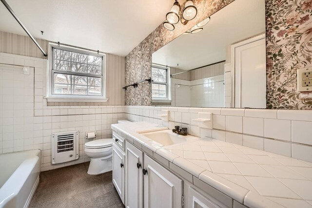 full bathroom featuring tile walls, heating unit, vanity, toilet, and tiled shower / bath