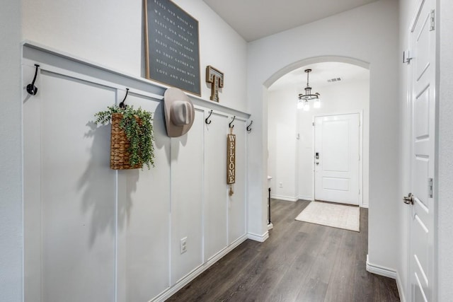 mudroom with dark wood-type flooring and an inviting chandelier