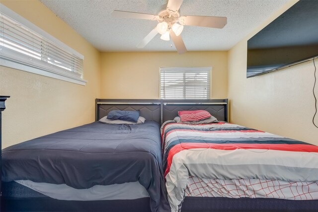 bedroom with ceiling fan and a textured ceiling