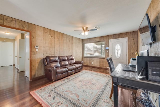 office with wooden walls, ceiling fan, and dark hardwood / wood-style flooring