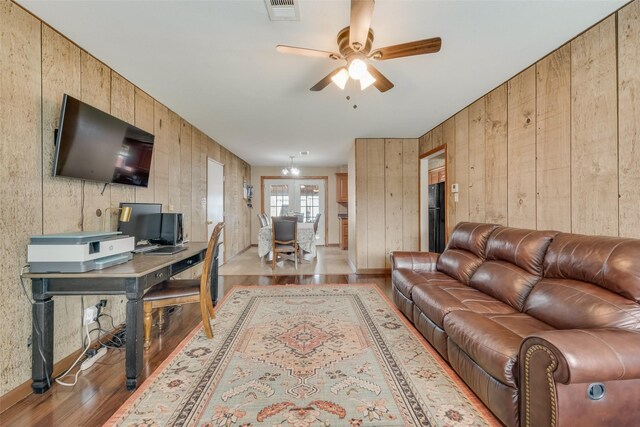 living room with wooden walls, light hardwood / wood-style floors, and ceiling fan