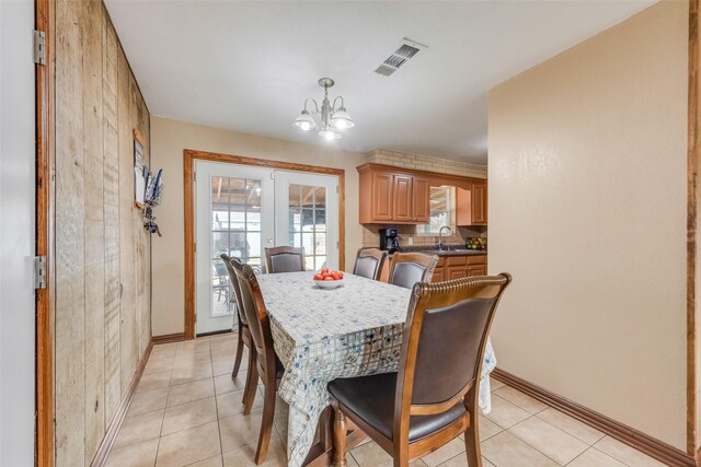 tiled dining space featuring french doors, a healthy amount of sunlight, a chandelier, and sink