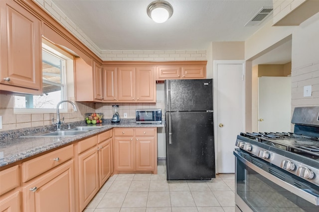 kitchen with sink, light stone counters, light tile patterned floors, stainless steel appliances, and backsplash