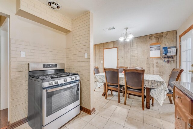 kitchen with gas range, brick wall, an inviting chandelier, and decorative light fixtures