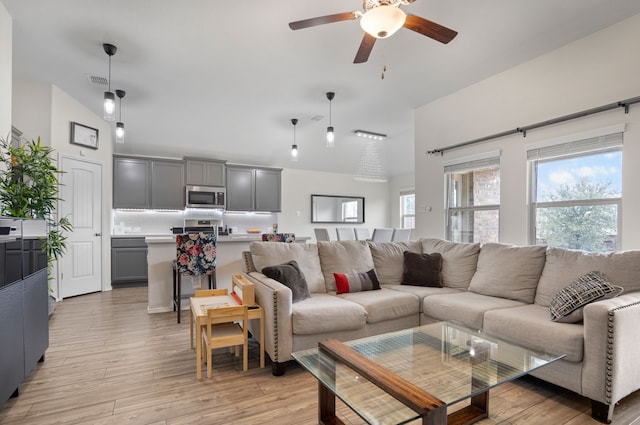 living room with visible vents, ceiling fan, high vaulted ceiling, and light wood-style flooring