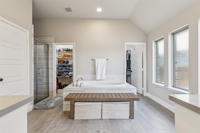 bathroom with hardwood / wood-style flooring, vaulted ceiling, and plus walk in shower