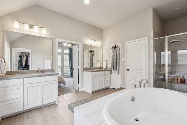 bathroom featuring independent shower and bath, vanity, lofted ceiling, and hardwood / wood-style floors