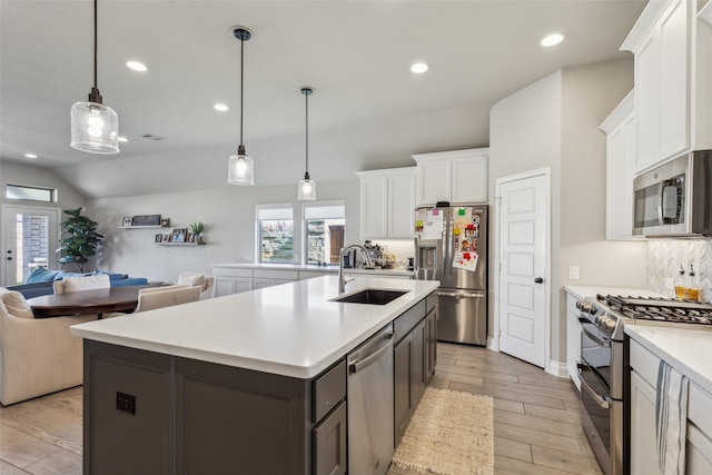 kitchen with sink, white cabinetry, hanging light fixtures, a center island with sink, and appliances with stainless steel finishes